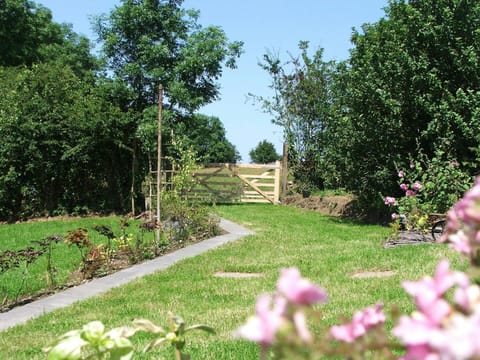 Lawn area with flower beds and gate leading to a meadow