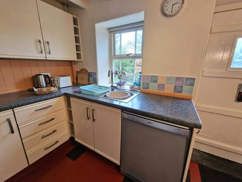 Kitchen with wall and base cupboards. Dishwasher, kettle, toaster and door leading to the garden