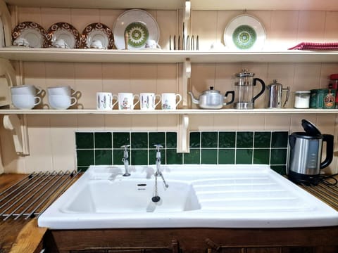 White ceramic kitchen sink, kettle and shelving displaying crockery
