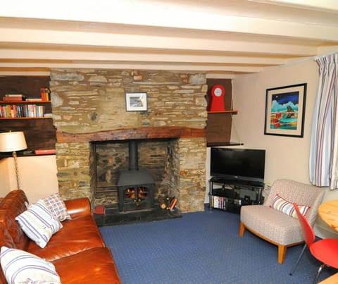Living room with leather sofa, armchair and fireplace. TV on stand.