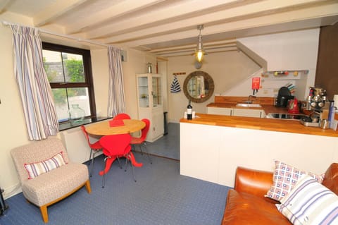 Open plan living area with sofa, armchair, dining table with four chairs