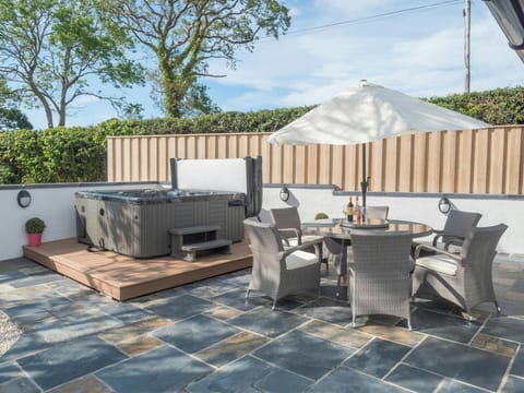 Hot tub, patio table, chairs and parasol in the garden