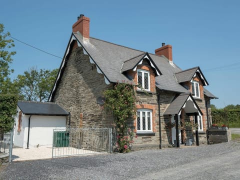 Outside view with gravel driveway, front porch and door, double metal gates