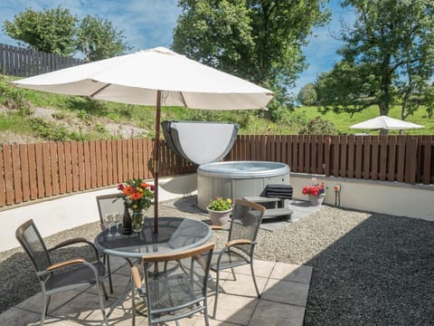Patio with rural views at Eirlys, hot tub, table, chairs and parasol