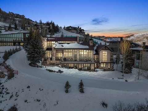 Luxury mountain home exterior at dusk with snow-covered slopes in Park City.
