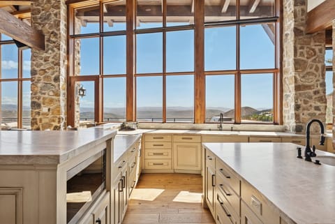 Kitchen with wraparound counters, farmhouse sink, and tall windows framing mountain views.