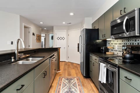 Stainless steel appliances incl. dishwasher, oven, stove, microwave, and fridge.