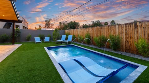 Enjoy the modern backyard with sleek pool, in-water loungers, and lush greenery.