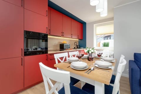 Modern kitchen with striking red cabinetry, wooden countertop, built-in appliances, and bright lighting.