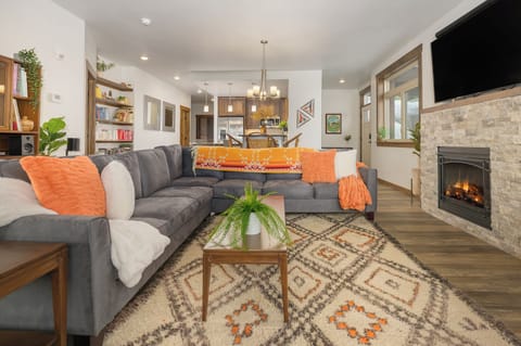 Sink into plush sectional seating while the stone fireplace crackles nearby, creating your perfect evening retreat in this open-concept living space.