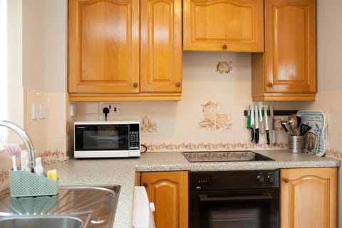 Wooden cabinets, oven, hob, microwave and utensils, magnetic knife rack