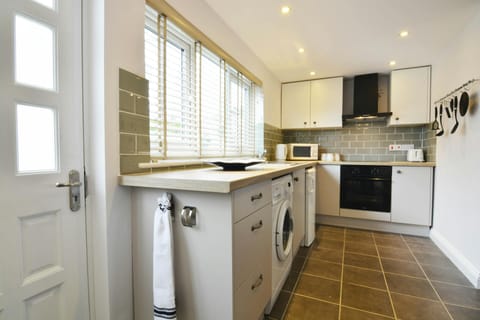 Kitchen with cooker, cooker hood, sink, washing machine, microwave, kettle and toaster