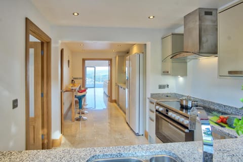 View from one end of kitchen past breakfast bar on left through to sitting room and terrace