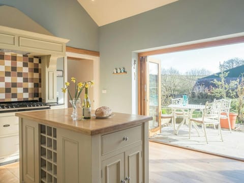 Kitchen island with wooden worktop and glass vase, open doors to patio seating