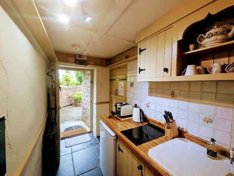 Kitchen with hob, sink, view into garden through back door