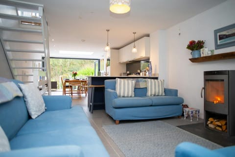 Two sofas and wood burner in the living room leading to the kitchen, stairs to the first floor
