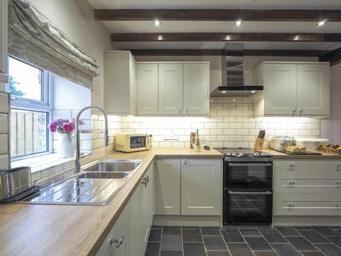 White wall and base units. Microwave. Window with blind looking over the garden