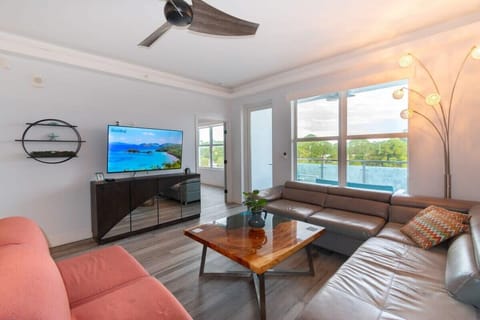 Modern living room with leather sectional, large windows, and a balcony view.