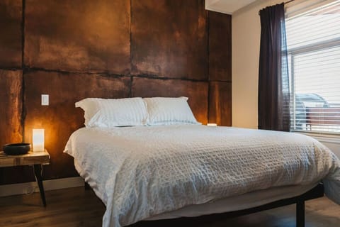 Our master bedroom features a queen bed, ambient lighting, and a moody wall feature.