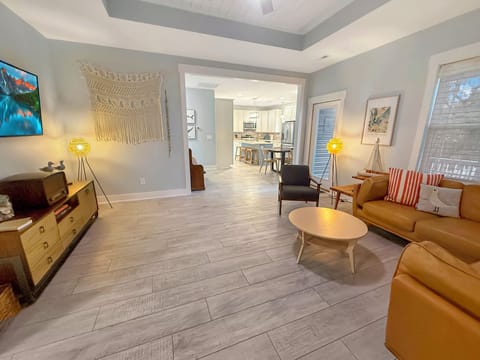 Bright open living room w/ chic decor, Smart TV, and flow to modern kitchen