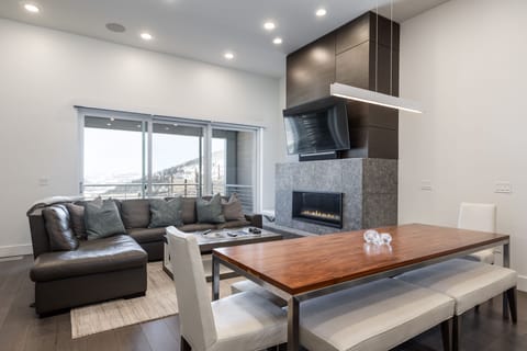 - Open living room with sectional sofa and modern stone fireplace  
- Large flat screen TV and sliding glass doors to balcony views  
- Inviting space for après-ski gatherings and cozy nights