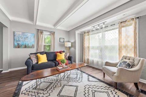 Bright living room w/ sofa seating, colorful accents & large windows letting in natural light