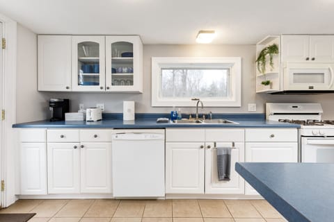 Step into our kitchen, where classic elegance meets modern charm. With pristine white cabinetry contrasting deep blue countertops, bathed in natural light from the glass door, it's a harmonious fusion of style and functionality that's sure to inspire culinary creativity.