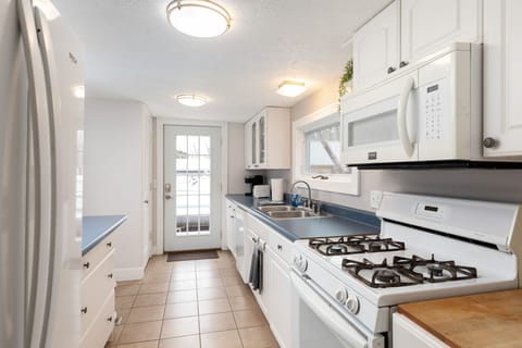 The kitchen is a vision of classic elegance with white cabinetry and deep blue countertops, bathed in the glow of natural light from the glass door. It's a harmonious blend of style and practicality.