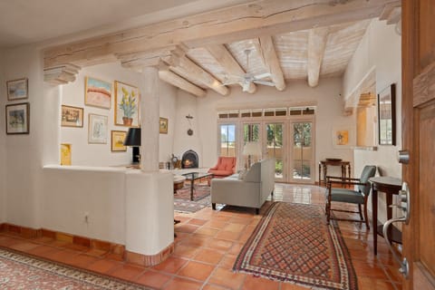 Unwind in the inviting living area, which features a cozy kiva fireplace, tall ceilings with white-washed lodge-pole beams, and large glass French doors leading to the private courtyard.