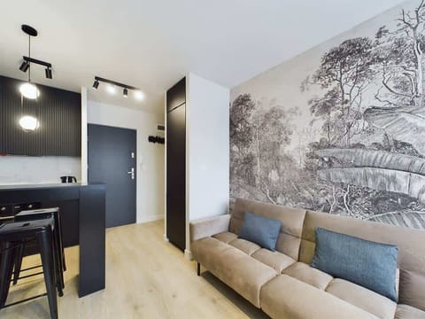 A living space with a stylish wallpaper depicting a classical scene. A light-colored couch and a dark table are visible.