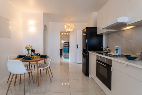 Modern kitchen open to a bright dining area, with a large refrigerator, oven, and a cozy dining nook.