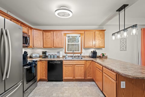 This kitchen has everything you need for food prep and cleanup, including a dishwasher and sink, with a dining table nearby for meals.