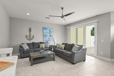 Modern living room with gray sofas and nautical decor featuring a sliding glass door to the patio.