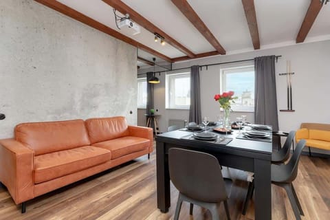 Bright living room with an orange sofa, black dining table, wooden flooring and exposed ceiling beams.