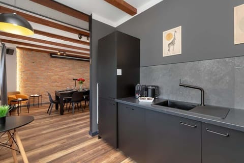 Modern kitchen with black cabinets, built-in appliances and brick wall accents.