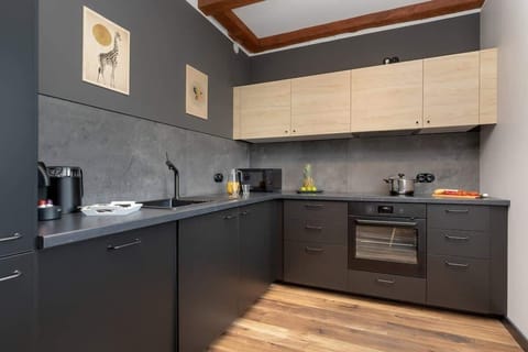 Modern kitchen with black cabinets, built-in appliances and brick wall accents.