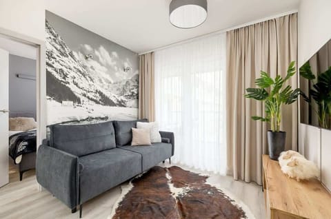 A cosy living room with a grey sofa and decorative wallpaper invites you to relax after a busy day.
