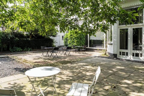 A peaceful outdoor garden with a cozy seating area under the shade of trees. Perfect for enjoying a cup of coffee or simply unwinding in the fresh air.