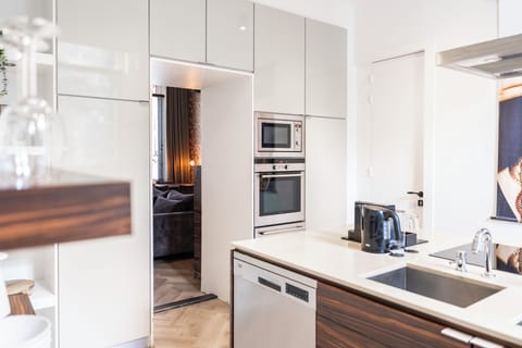 Sleek, modern kitchen with high-gloss cabinets, built-in appliances, and a wood-accented island. Clean lines and neutral tones create a bright, refined space.