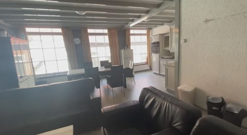 A spacious living room featuring large windows that bathe the area in natural light, complemented by modern furnishings for a comfortable urban living experience.