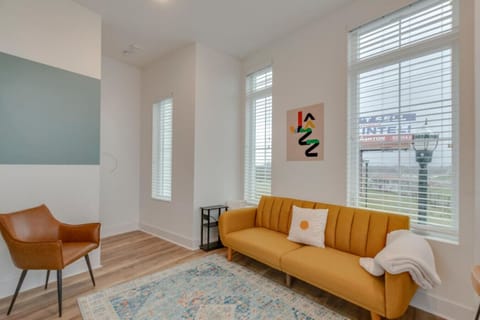 A cozy living room with a mustard velvet couch, warm tones, and large windows lets in beautiful natural light.