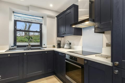 Modern kitchen with dark cabinets, white worktops, built-in oven and hob