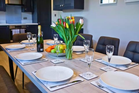 Dining table set with plates, cutlery and glasses, with tulips and fruit in the centre