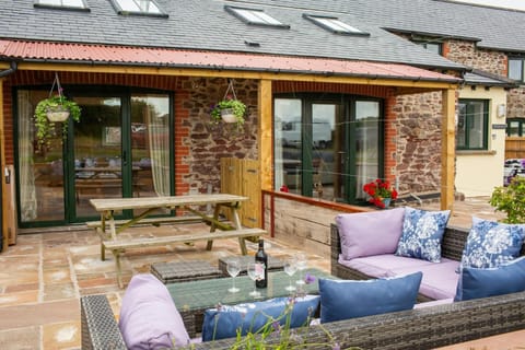 Rattan effect outside sofas and coffee table. Picnic table and patio doors leading to cottage