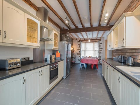 Long kitchen with cabinets each side, oven, hob, toaster and kettle