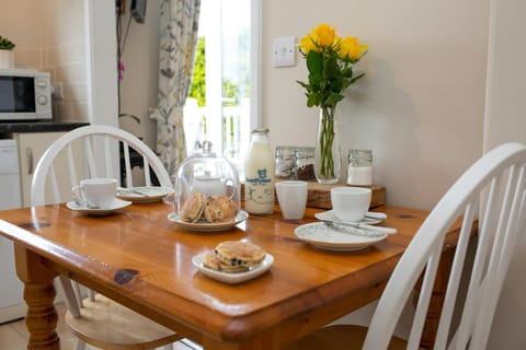 Dining table dressed for dinner for two with welsh cakes and fresh milk, yellow roses in a vase