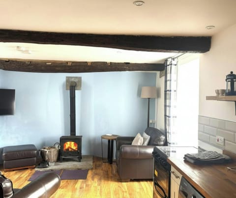 Living room with wood-burning stove, exposed beams, and leather seating