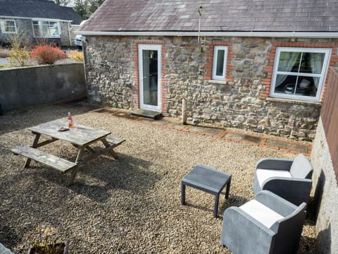 Outside gravelled patio area with picnic bench, outdoor armchairs and small table