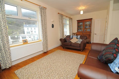 Main open plan living room with two leather sofas, wooden chair and dresser