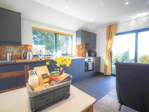 Kitchen area on one side with table and chairs, welcome pack and sofa on the other side